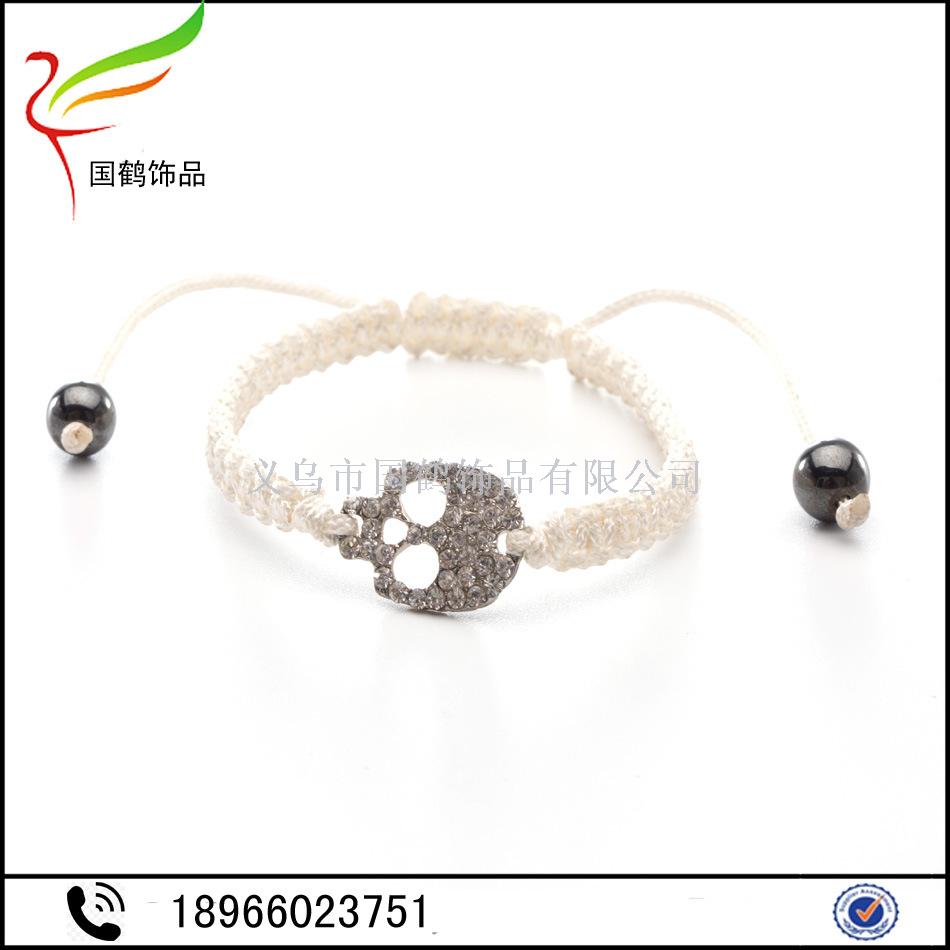 Diamond-encrusted skull with hand woven men&#039;s bracelet.